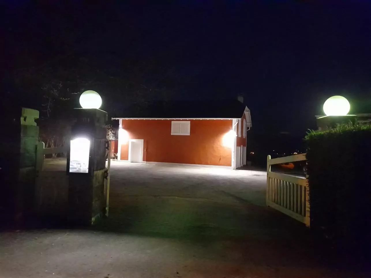 Cour éclairée la nuit, globes sur les piliers